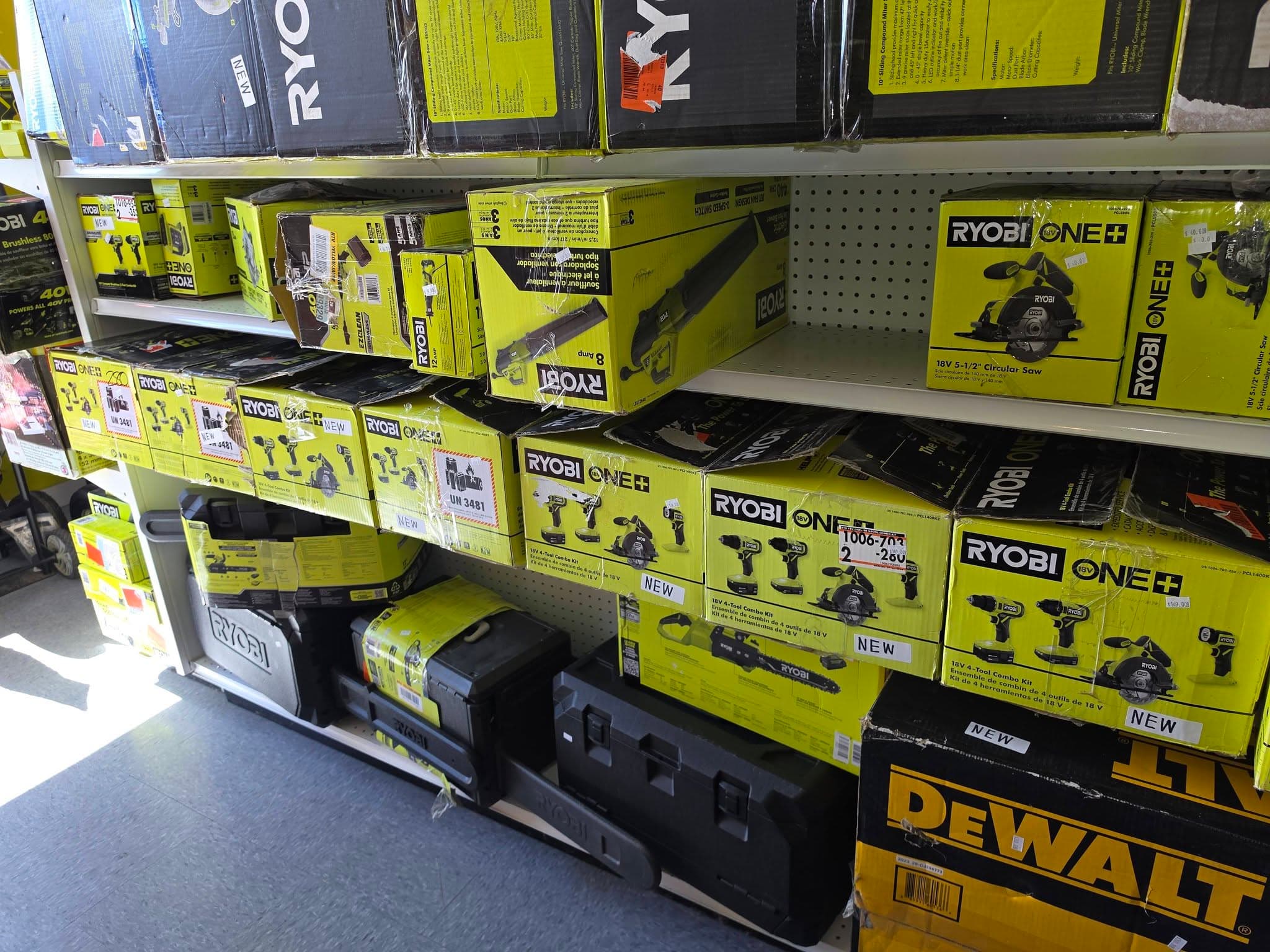 Shelves stocked with lime green Ryobi power tool boxes and a yellow DeWalt box.