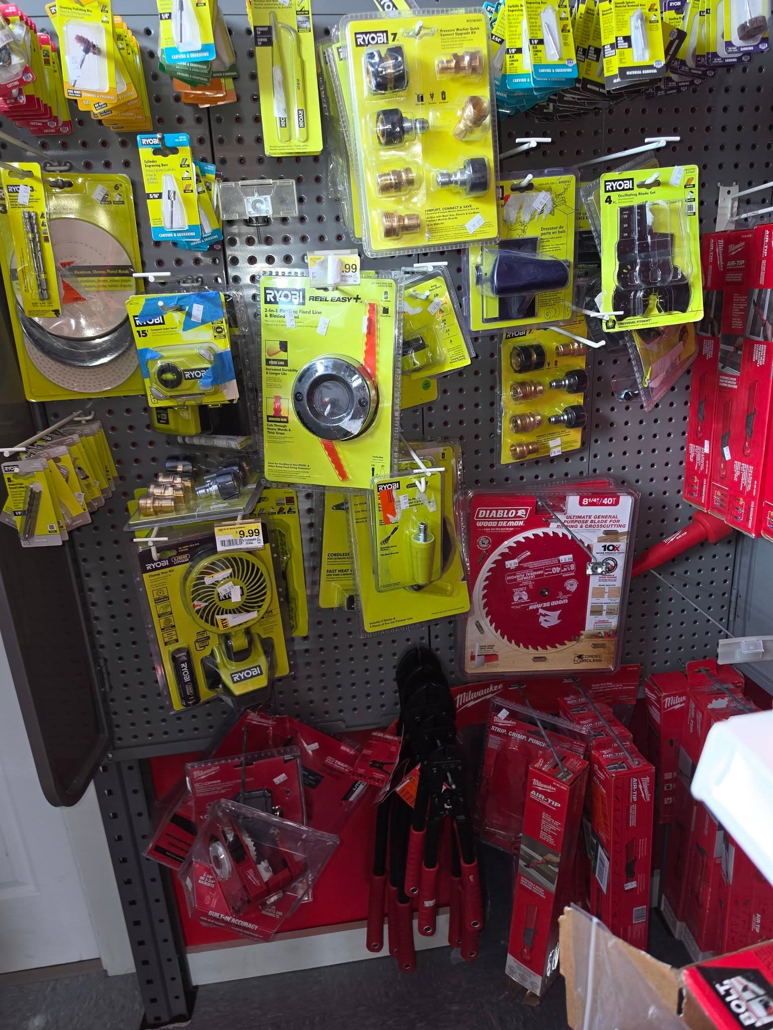 Pegboard display with packaged Ryobi, Diablo, and Milwaukee power tool accessories and hand tools.